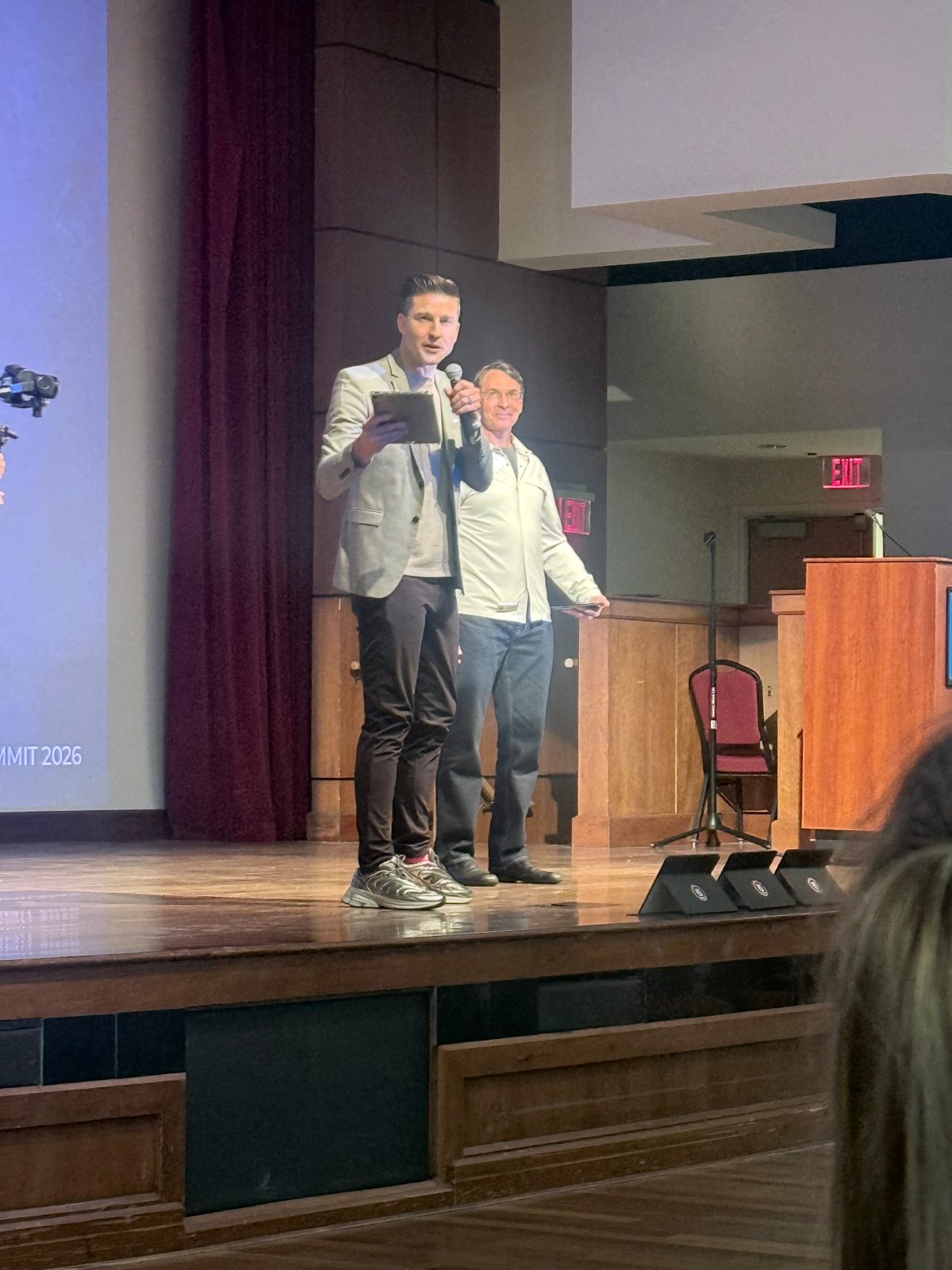Gary Tuerack and Tom Krieglstein standing together on the summit stage, one holding a microphone